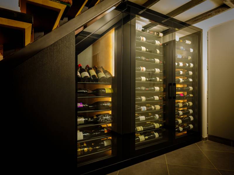 Armoire à vins en verre intégrée sous l’escalier d’un appartement à Lyon